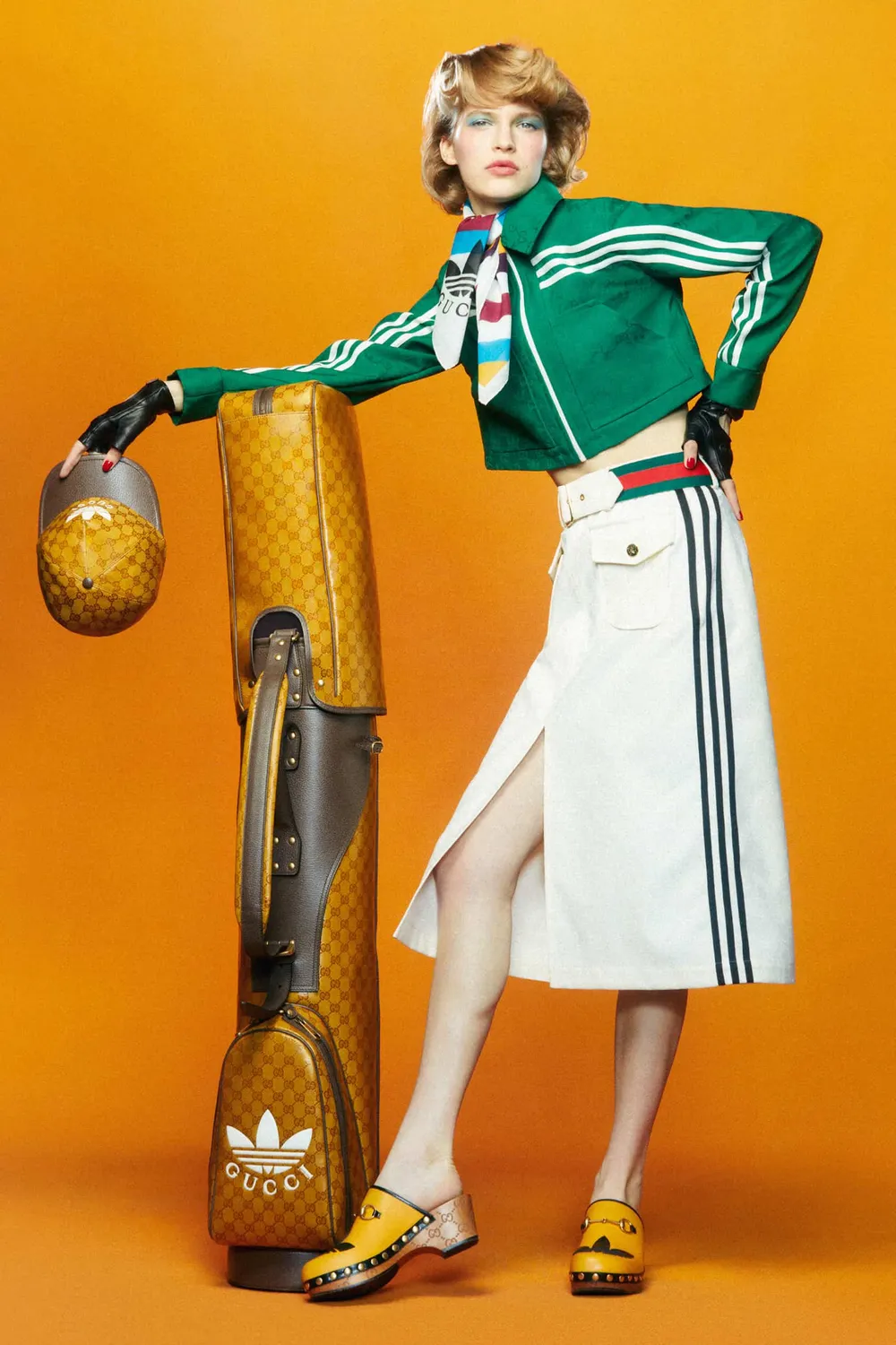 Gucci x adidas lookbook photo of a model in a green track jacket and white skirt